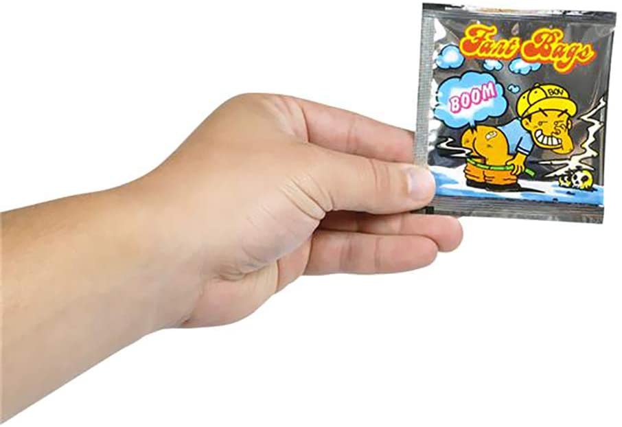 A hand holding a packet of "15 Fart Stink Bombs Nasty Smelly Butt Ass Gas Odor Bags - Party Favors Joke" featuring a cartoon of a boy and a cloud labeled "BOOM," perfect for prank toy enthusiasts. Ideal for those looking to add humor to their collection, whether purchasing individually or considering wholesale options.